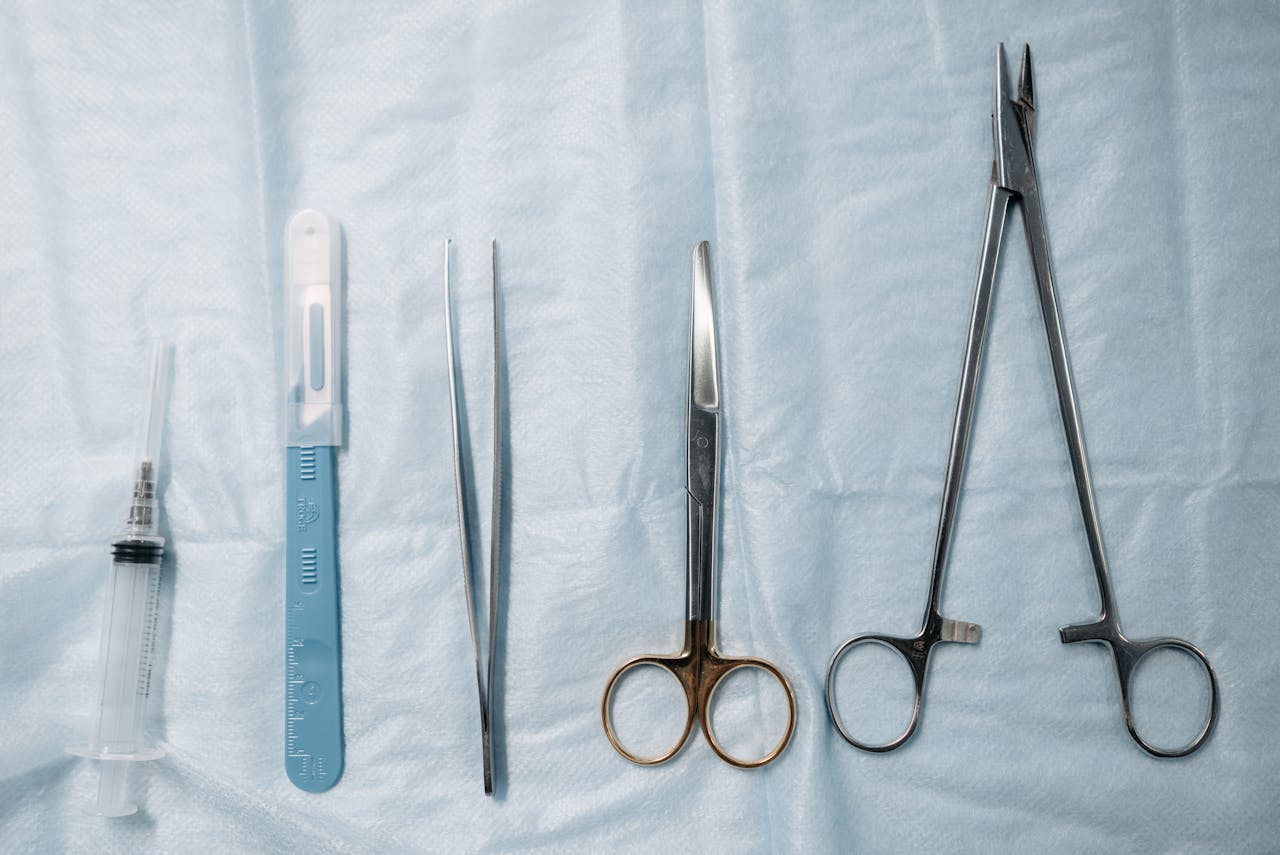 services-04 Flat lay of surgical tools including scissors, forceps, and syringe on a sterile blue cloth.