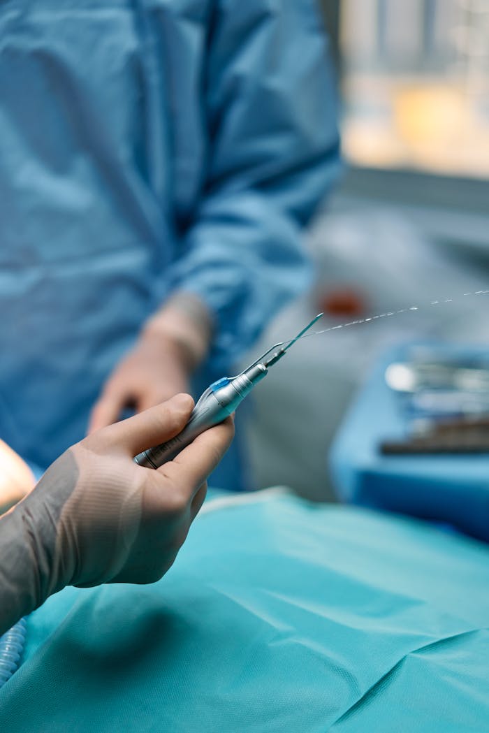 services-01 Detailed view of a surgeon's hand using a surgical tool in a hospital setting.